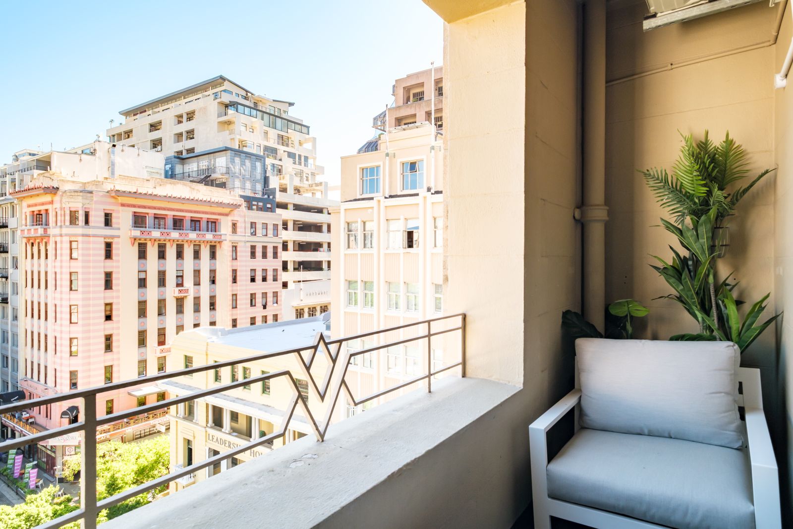 Balcony with two chairs and a small table, the square below